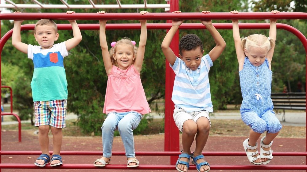 Kids playing on red monkey bars at a park playground