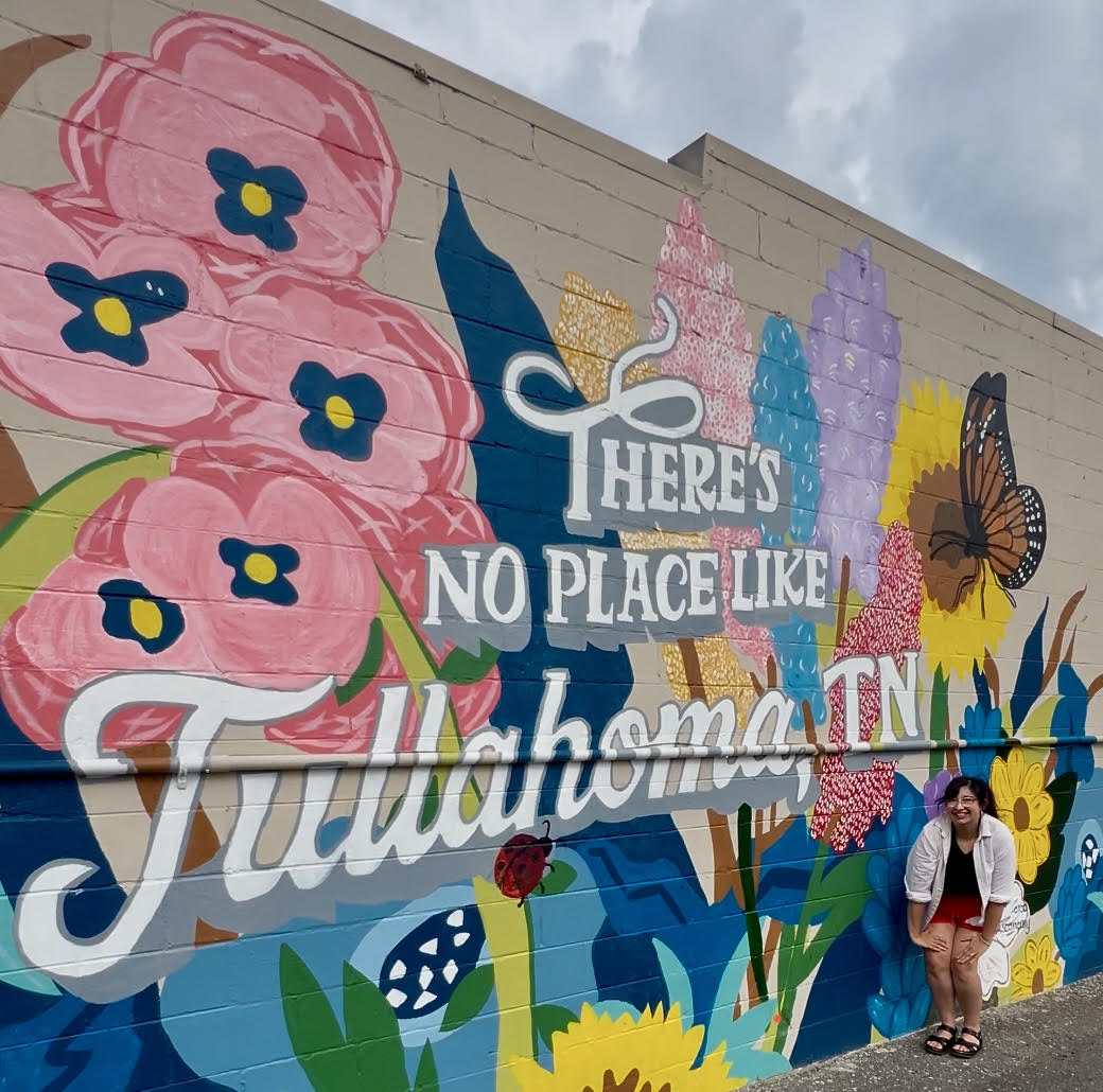 Jennifer smiling in front of the flower-covered "There's No Place Like Tullahoma, TN" mural