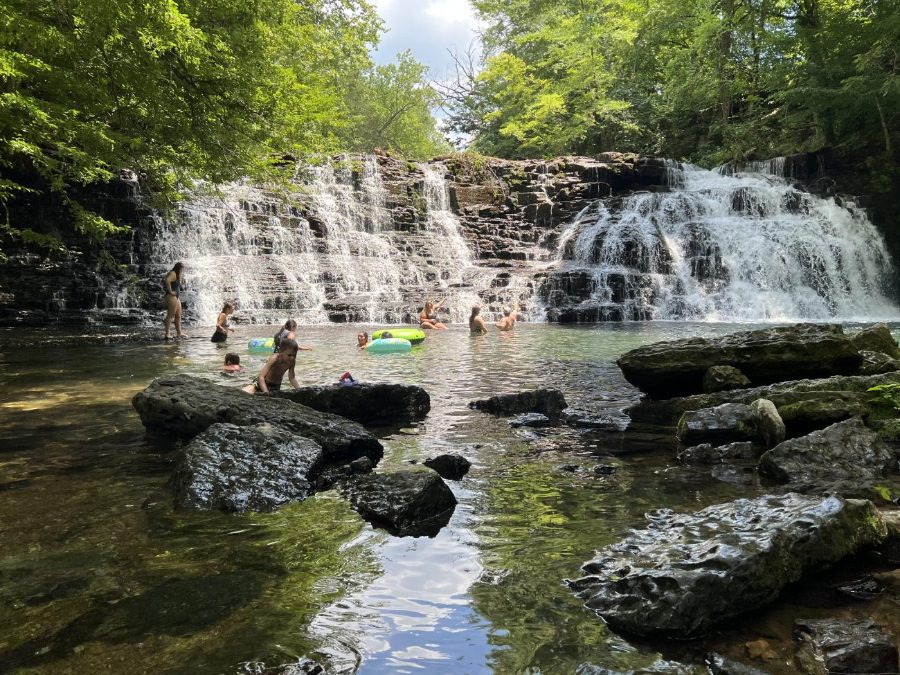 Families swimming in the pool below a wide Tennessee waterfall